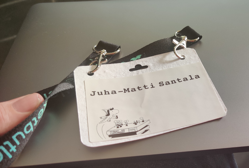 A white, organic looking badge with a sticker with Django Day Copenhagen logo and my name on it