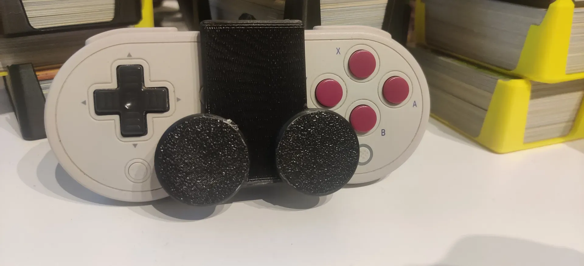 A gaming controller with a black, 3D printed cover covering the middle bit and two thumbsticks 