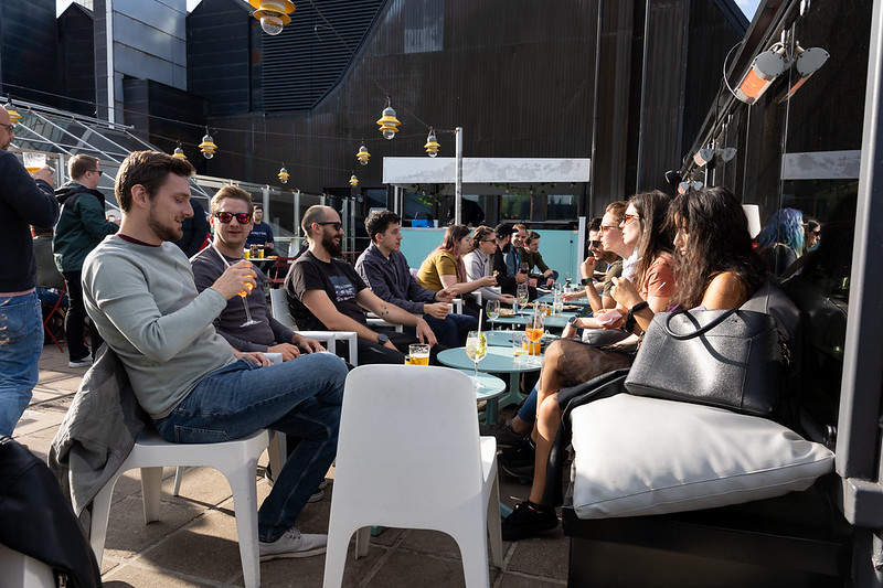 A row of tables on a terrace of a pub, full of people having drinks. 