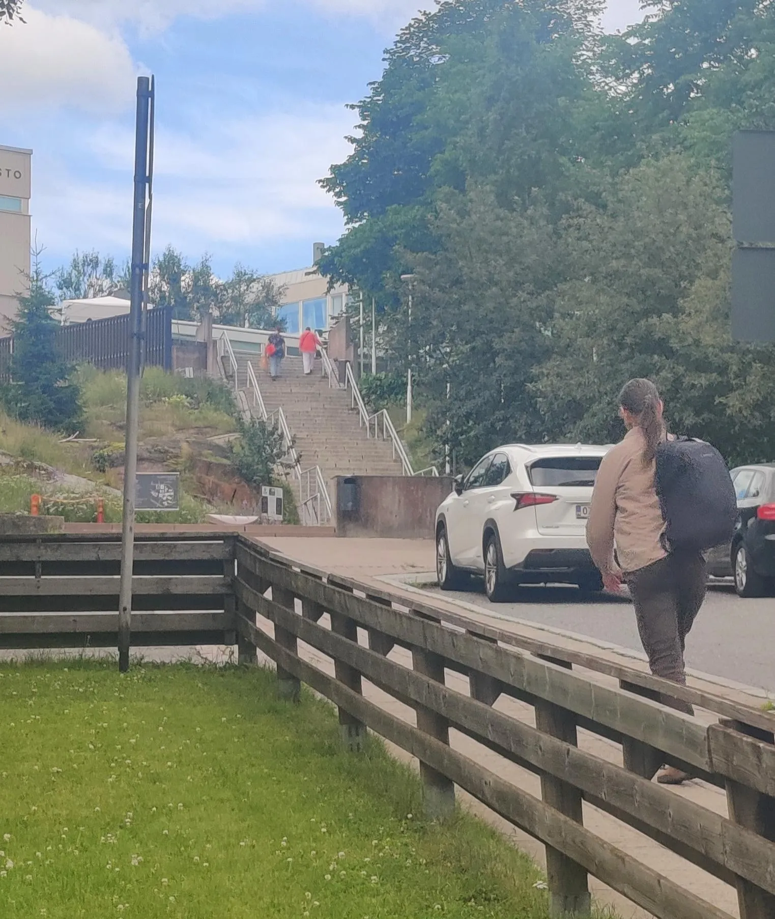 A street end leading to a set of stairs at a university campus. It’s a sunny summer day and a couple of people are climbing the stairs. 