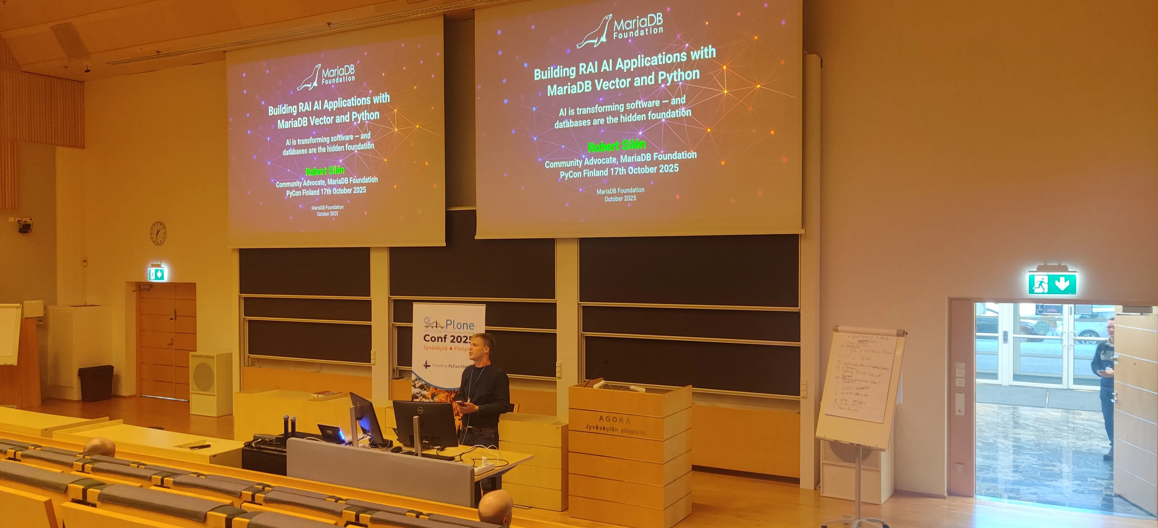 Robert speaking in front of an auditorium with a title slide about building RAG AI applications with MariaDB Vector and Python 