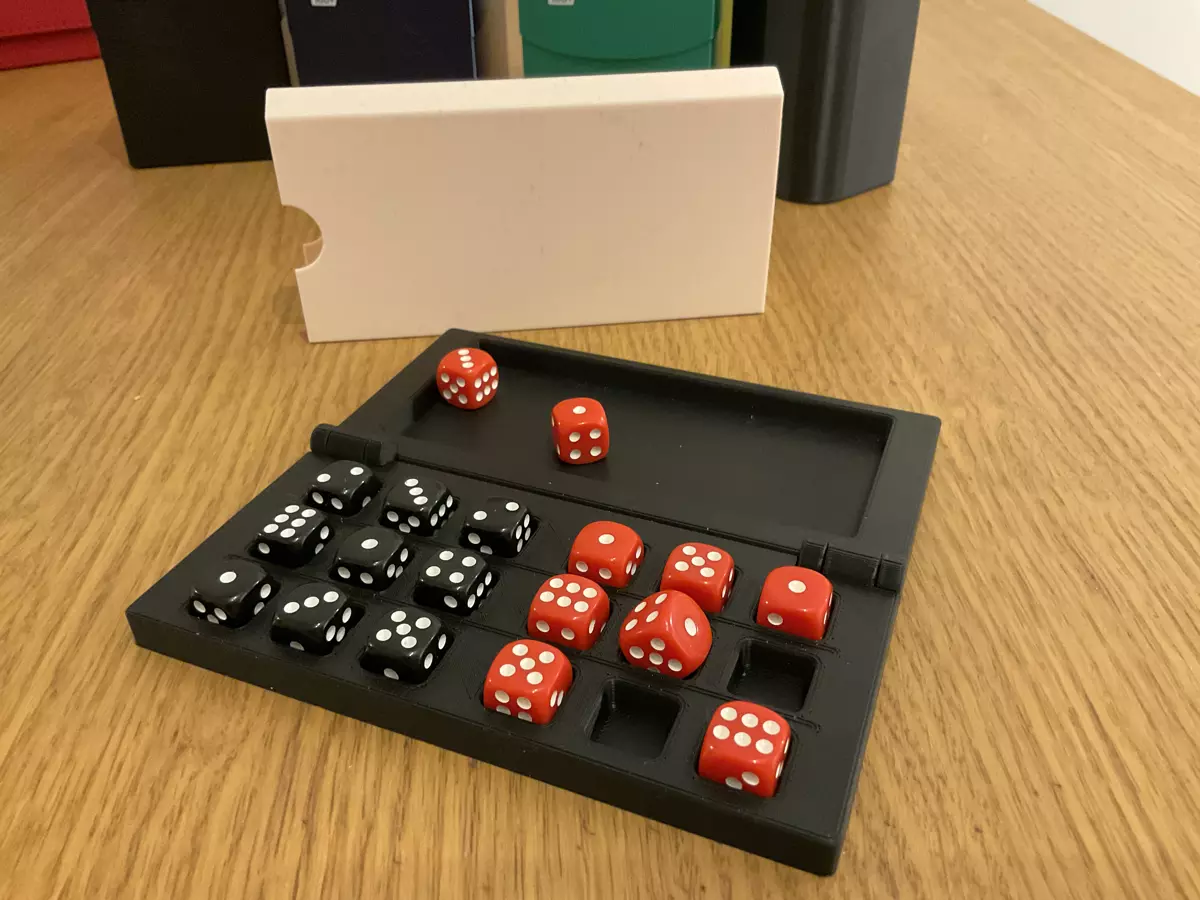 A black 3D printed case with space for 18 small dice and on the other side of the hinge, an area for rolling dice. There are 9 black dice and 9 red dice in the board.