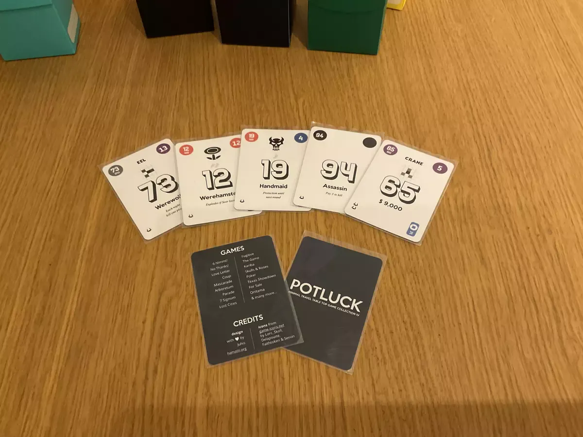 Five white cards fanned out, showing numbers 73, 12, 19, 94 and 65 as well as a variety of other graphical elements all around the cards. In front of those cards, one card showing its back with large title Potluck and dark blue background. Another card shows a list of games in a small font as well as credits for the design and artwork in small font. 