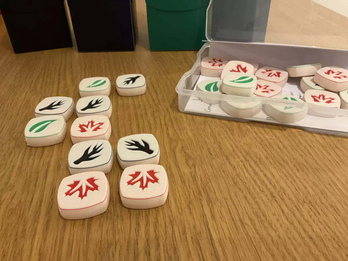 Couple of white 3D printed tiles with black branches and red and green leaves in a grid-like setting. 