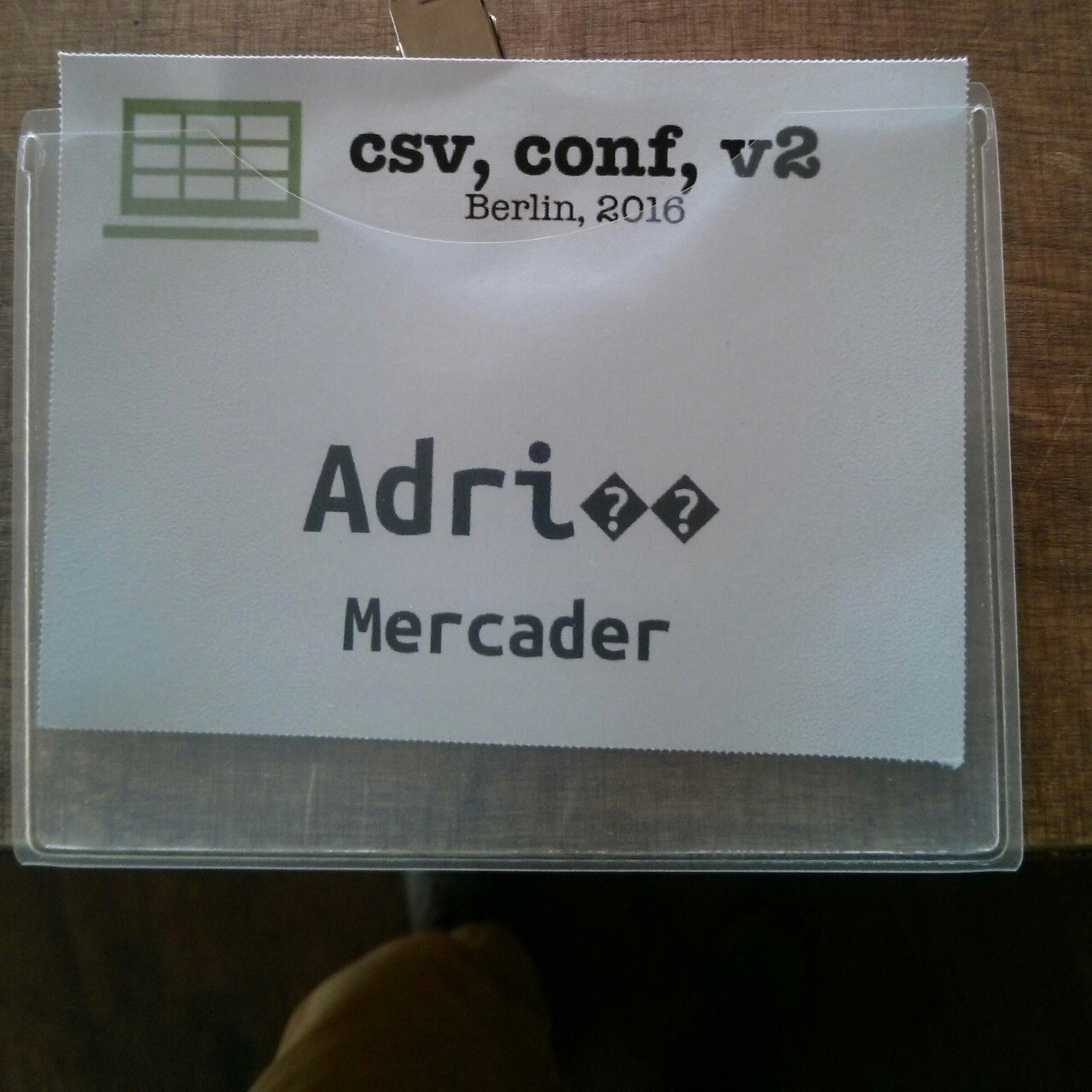 A conference badge of csv, conf 2016 for Adrià Mercader with first name written as “Adri” followed by two question marks in black triangles.
