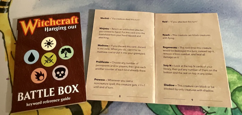 Two booklets: one showing a cover for Battle Box keyword reference guide and another showing a full spread with 10 Magic keywords explained. 
