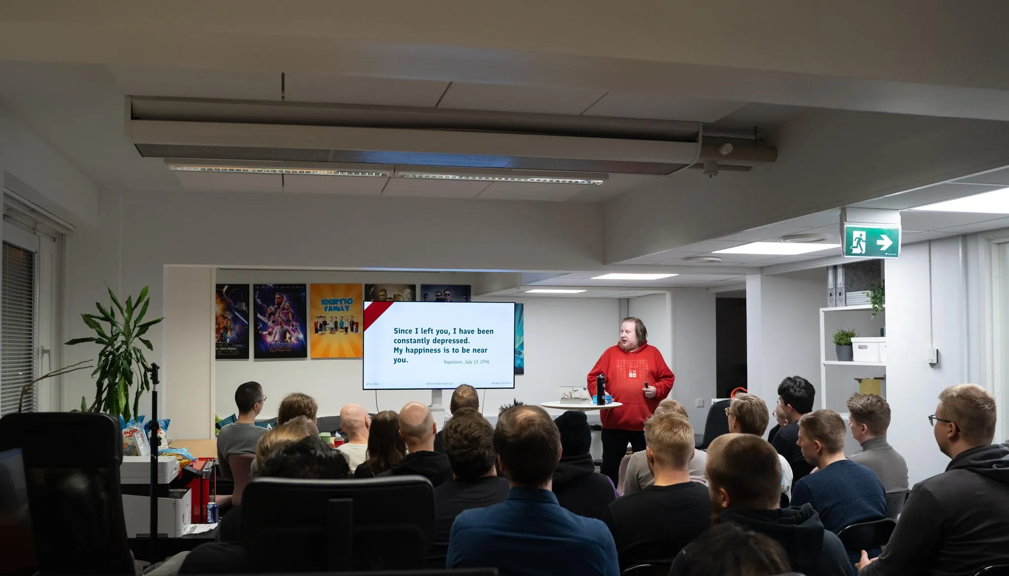 Juhis is speaking in front of a small audience in an office space. 